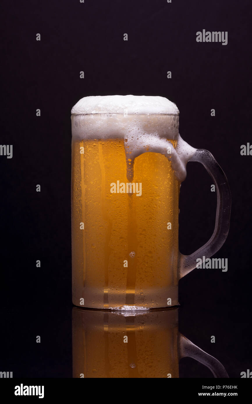 Cold cup with beer and foam, with reflection Stock Photo