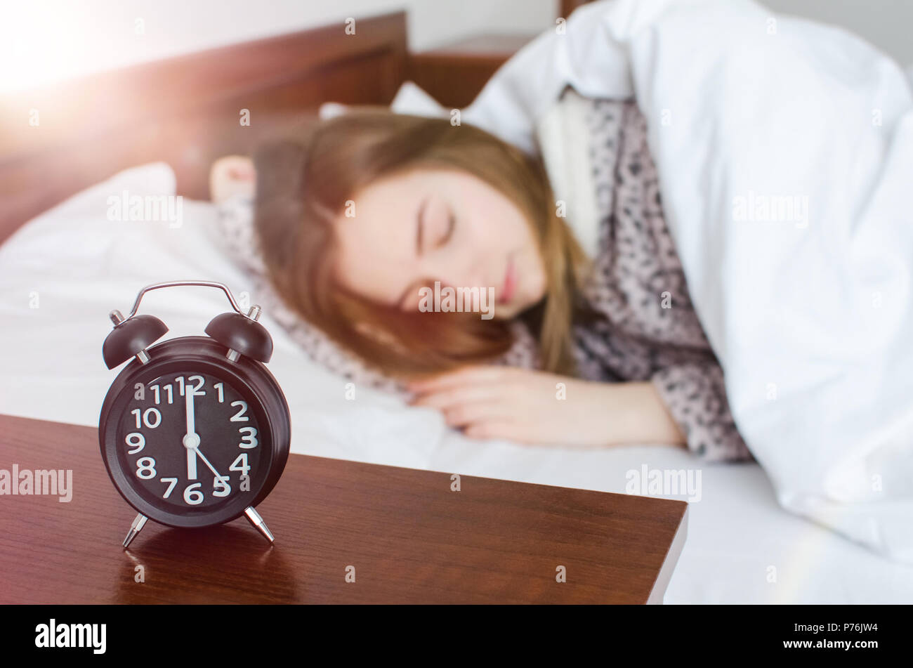 Young woman sleep with alarm clock near the bed in the morning. Sleeping girl and alarmclock in