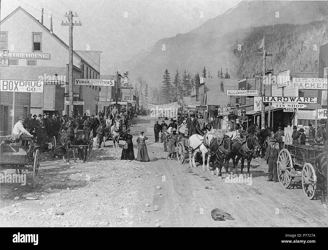 . English: Broadway, Skagway, Alaska, May 20, 1898. English: Shows two women and horse drawn wagons in street, Headquarters Yukon Outfitters on left, Getz & Donovon Packers and Dyea Mercantile & Mining Co. on right Original image in Hegg Album 7, page 13 . Klondike Gold Rush. Subjects (LCTGM): Streets--Alaska--Skagway; Carts & wagons--Alaska--Skagway; Horses--Alaska--Skagway; Business districts--Alaska--Skagway Subjects (LCSH): Broadway (Skagway, Alaska); Yukon Outfitters (Skagway, Alaska); Getz & Donovan Packers (Skagway, Alaska); Dyea Mercantile & Mining Company (Skagway, Alaska)  . 1898 2 B Stock Photo