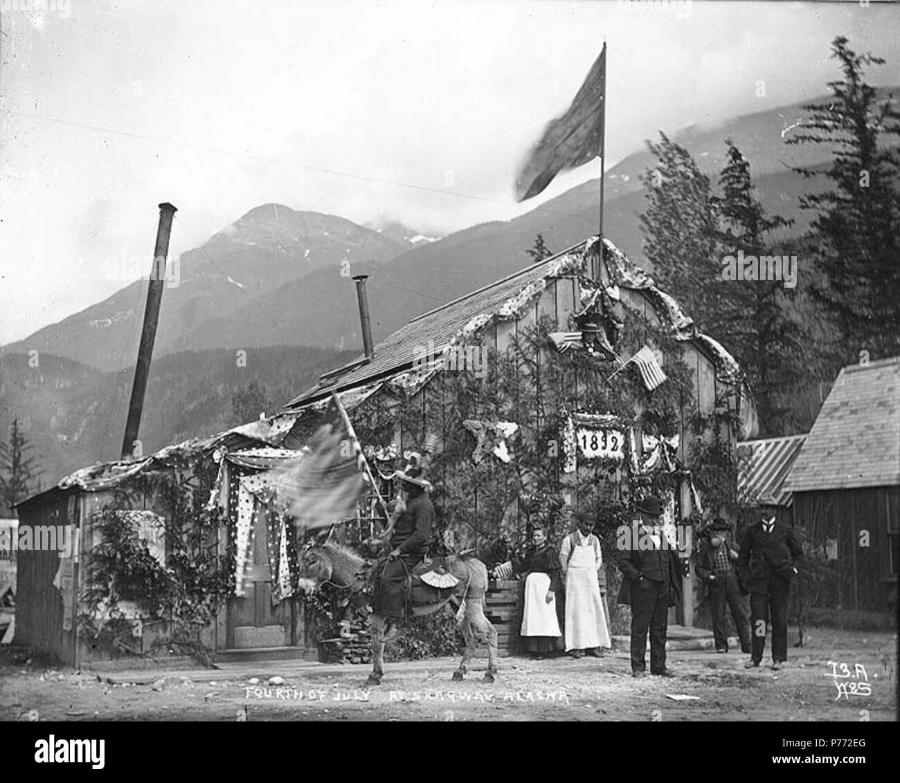 . English: City Hall decorated for July 4th celebration, Skagway, Alaska, 1898. English: On verso of image: 'A few of the City Fathers and the city hall decorated for the famous fourth of July, 1898. Yankee Doodle and his pony adorned with flags and fans joined the parade with its noisy brass band and its patriotic airs.' Caption on image: 'Fourth of July at Skagway, Alaska' Original image in Hegg Album 7, page 39 . Original photograph by Eric A. Hegg 602A; copied by Webster and Stevens 73.A. Subjects (LCTGM): Fourth of July celebrations--Alaska--Skagway; City & town halls--Alaska--Skagway  .  Stock Photo