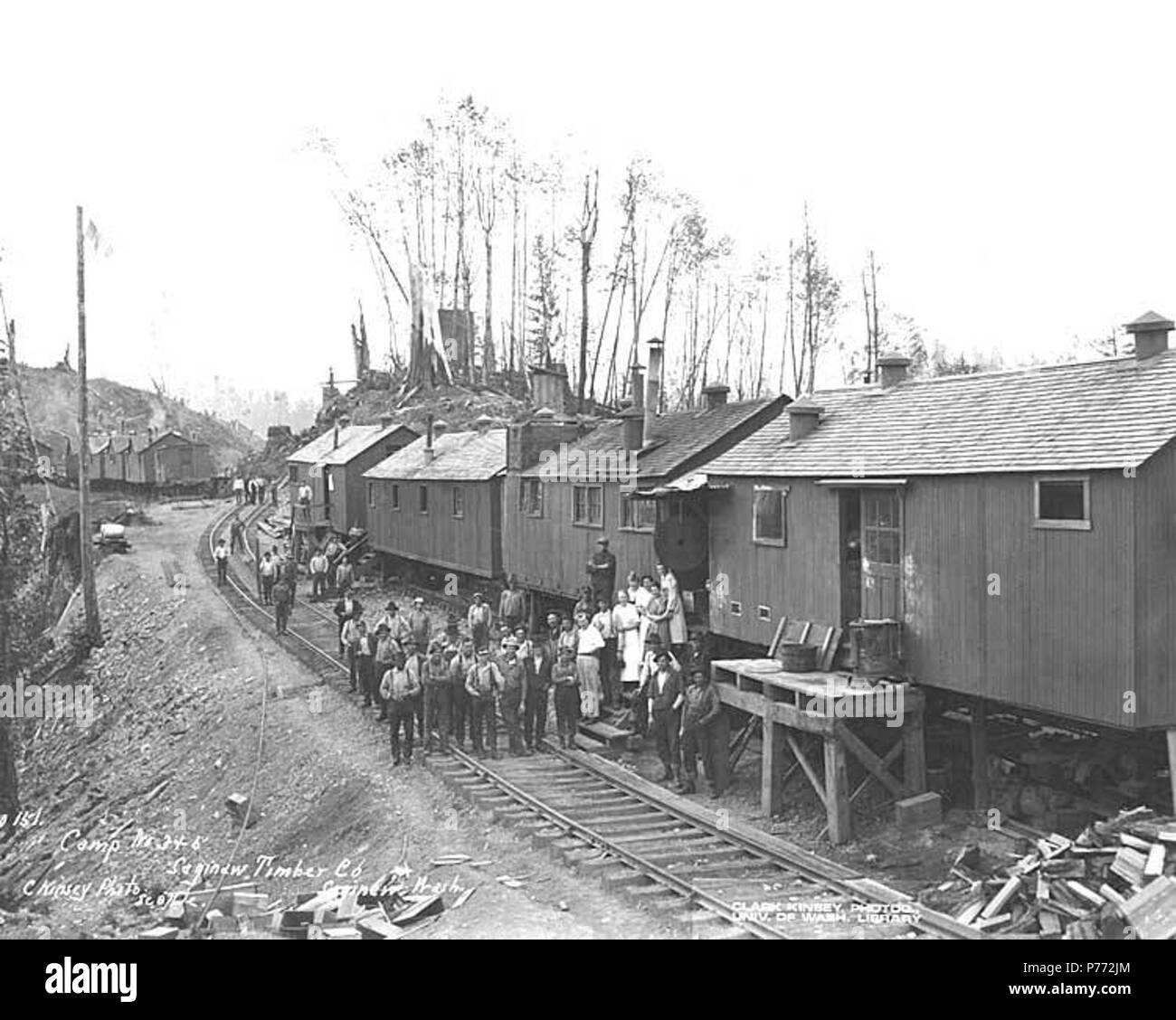 . English: Crew at camps 3 and 5, with mess hall crew standing on steps of mess hall with saw blade dinner gong, Saginaw Timber Company, Saginaw, ca. 1918 . English: Caption on image: Camp No. 3 & 5, Saginaw Timber Co., Saginaw, Wash. C. Kinsey Photo, Seattle. No. 151 PH Coll 516.3198 The Saginaw Timber Company incorporated on March 18, 1908 and organized in 1909. The company was to be capitalized at $100,000. The organizers were A J Morley and W G Hopkins. The company constructed and operated a 40 mile logging railroad in the Aberdeen area. In 1919, the company merged the E H Lester Logging C Stock Photo