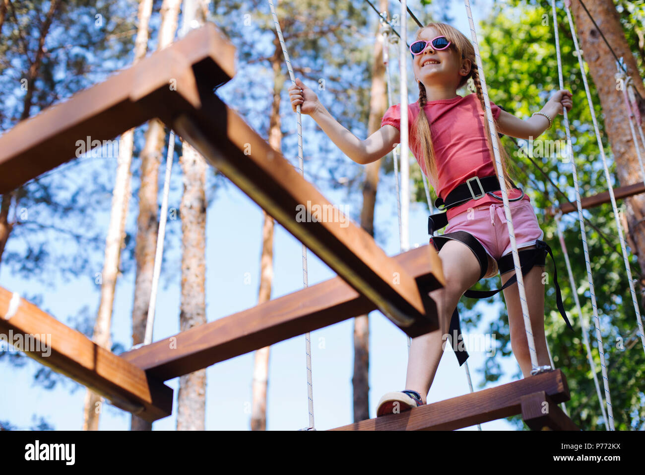 Cute little girl moving around rope park Stock Photo