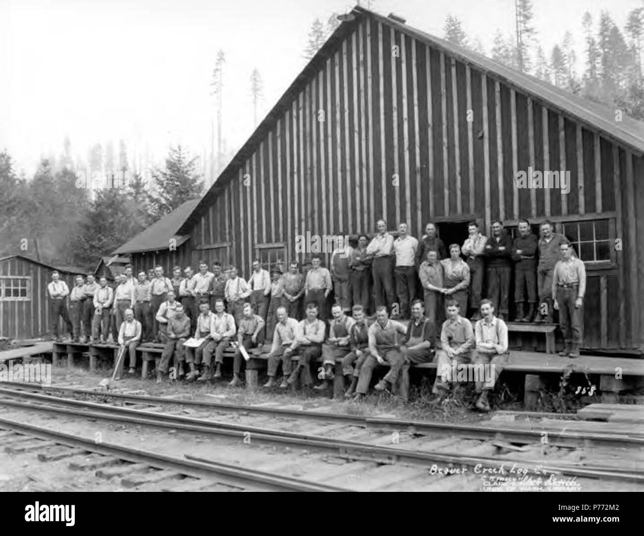 . English: Crew posing at camp behind railroad tracks, Beaver Creek Logging Company, Vernonia, ca. 1922 . English: This company probably operated in Vernonia, Oregon with headquarters in Portland and became the Connacher Logging Company in 1925. Caption on image: Beaver Creek Log Col, No. 858 PH Coll 516.60 Subjects (LCSH): xyz  . circa 1922 3 Crew posing at camp behind railroad tracks, Beaver Creek Logging Company, Vernonia, ca 1922 (KINSEY 2086) Stock Photo