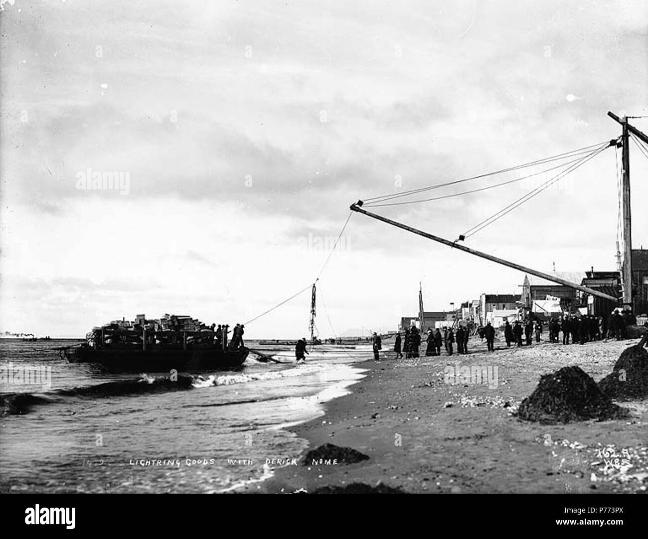 . English Lightering goods from a scow onto the beach, Nome, Alaska, ca. 1900. English Caption
