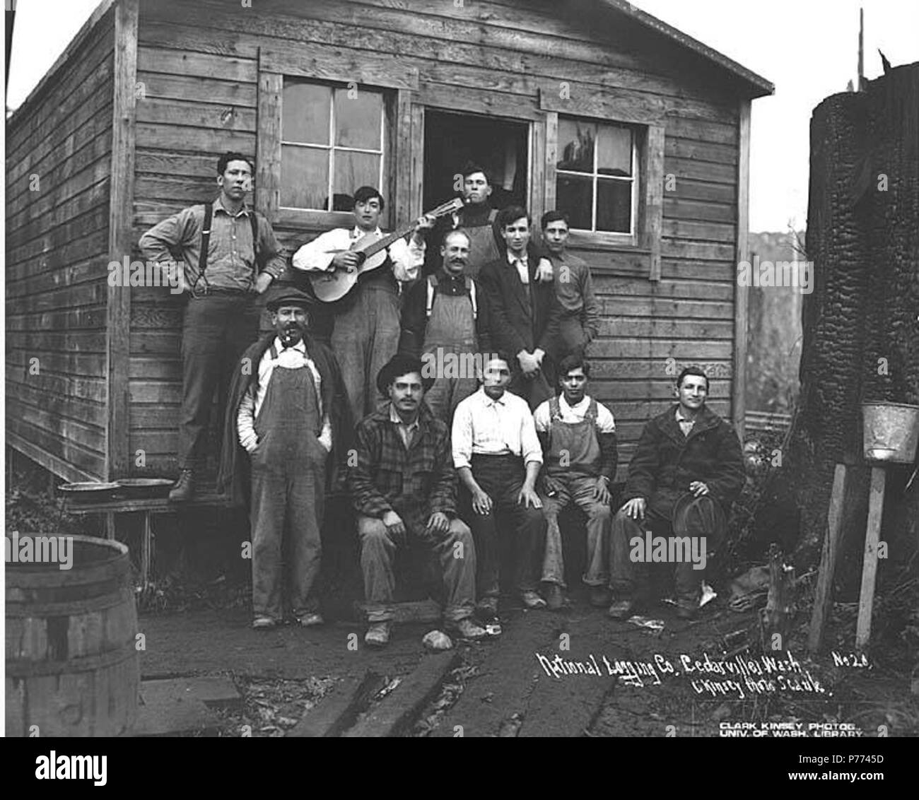. English: Logging crew at bunkhouse, National Lumber and Manufacturing Company, ca. 1920 . English: Caption on image: National Logging Co., Cedarville, Wash. C. Kinsey Photo, Seattle. No. 20 PH Coll 516.2231 The National Lumber & Manufacturing Company was in business from 1920 to 1927, with headquarters and mill in Hoquiam and logging operations first in Cedarville and then, by 1924, in Elma. National Lumber was sold to Polson Lumber Company in 1927. Cedarville is a small settlement near the Chehalis River, eleven miles southeast of Elma, in southeast Grays Harbor County. In 1855, it was esta Stock Photo