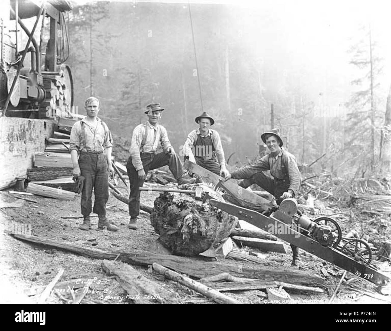 . English: Logging crew with gasoline-powered dragsaw beside donkey engine, Wynooche Timber Company camp no. 3, ca. 1921 . English: Caption on image: Camp No. 3, Wynooche Tmbr Co. C. Kinsey Photo, Seattle. No. 790 PH Coll 516.5218 The Wynooche Timber Company began operations ca. 1913 with headquarters in Hoquiam and logging operations in Montesano. It was named for Wynooche Valley in northeast Grays Harbor County. Wynooche Timber Company was bought out by Schafer Brothers Logging Company ca. 1927. Subjects (LCTGM): Wynooche Timber Company--People--Washington (State); Wynooche Timber Company--E Stock Photo