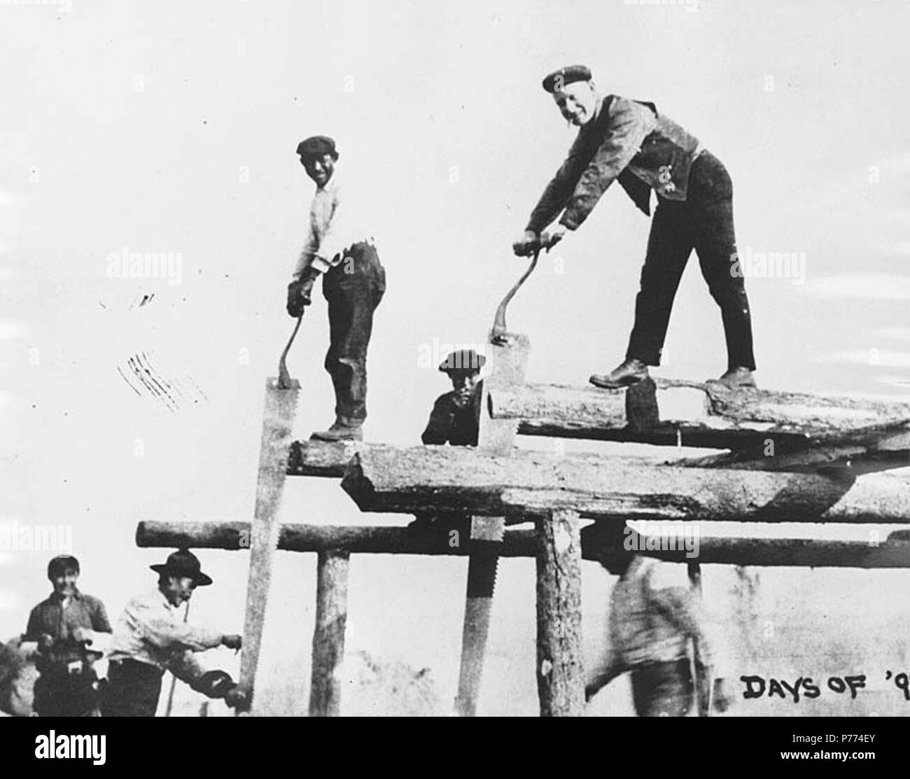 . English: Men whipsawing lumber, Bennett, British Columbia, 1898. English: Caption on image: 'Days of '98 saw mill' Klondike Gold Rush. Subjects (LCTGM): Lumber industry--British Columbia--Bennett; Woodcutting; Saws--British Columbia--Bennett; Sawmill workers--British Columbia--Bennett  . 1898 9 Men whipsawing lumber, Bennett, British Columbia, 1898 (HEGG 365) Stock Photo