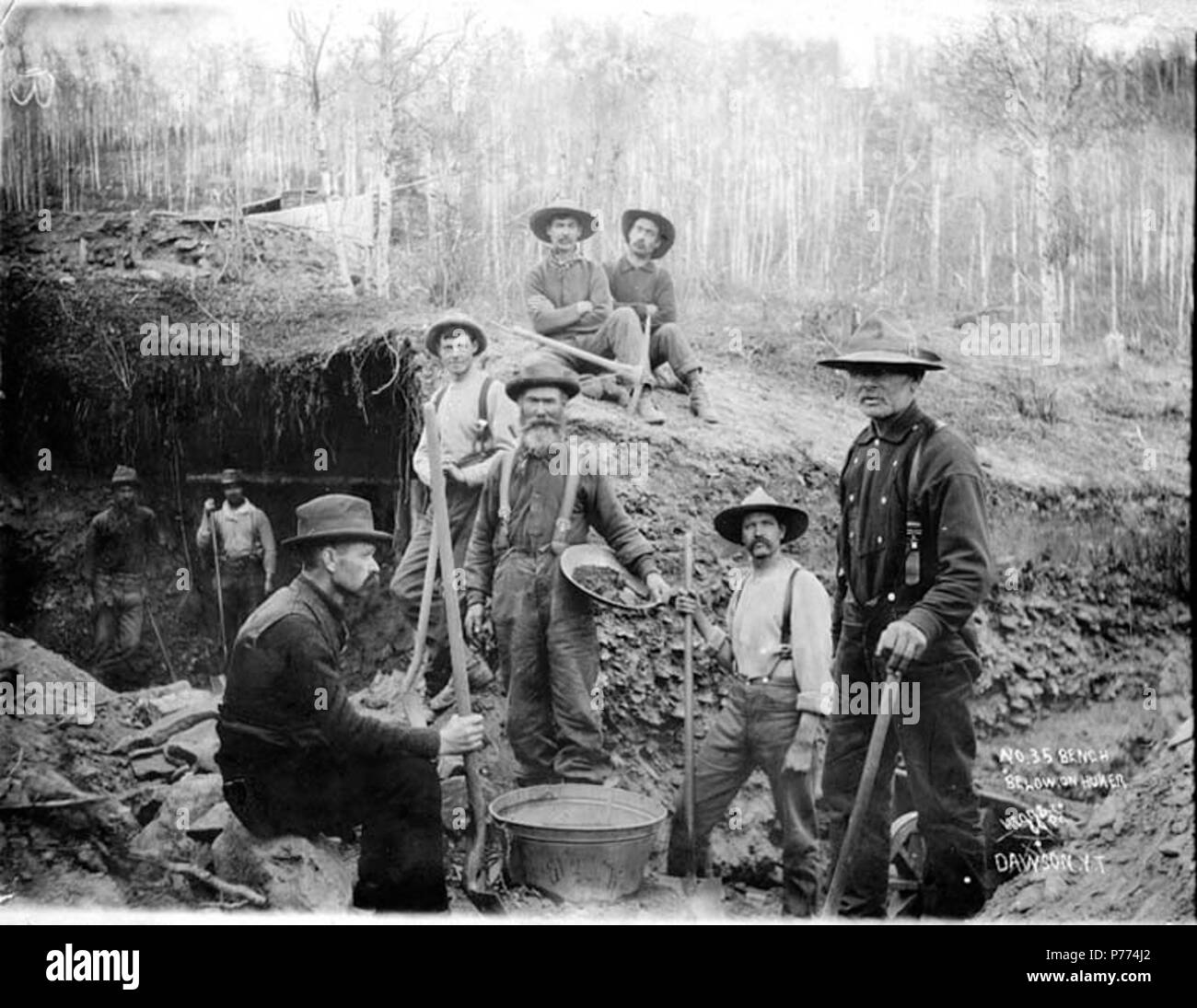 . English: Miners working the No. 35 bench claim below Hunker Creek, Yukon Territory, ca. 1898. English: Shows men with pickaxes, shovels and gold pan. The man in the foreground on the right is Desire Bourbonnais of Montreal Quebec . Caption on image: 'No. 35 Bench below Huner' Klondike Gold Rush. Subjects (LCTGM): Gold miners--Yukon--Hunker Creek; Gold mining--Yukon--Hunker Creek; Yukon--Gold discoveries  . circa 1898 9 Miners working the No 35 bench claim below Hunker Creek, Yukon Territory, ca 1898 (HEGG 155) Stock Photo