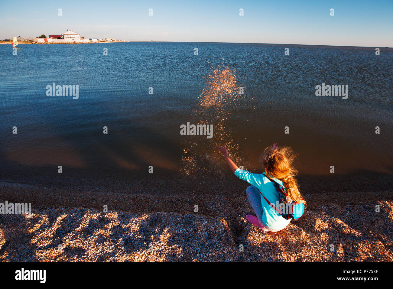 Seven years old girl on the beach at sunset time. Stock Photo