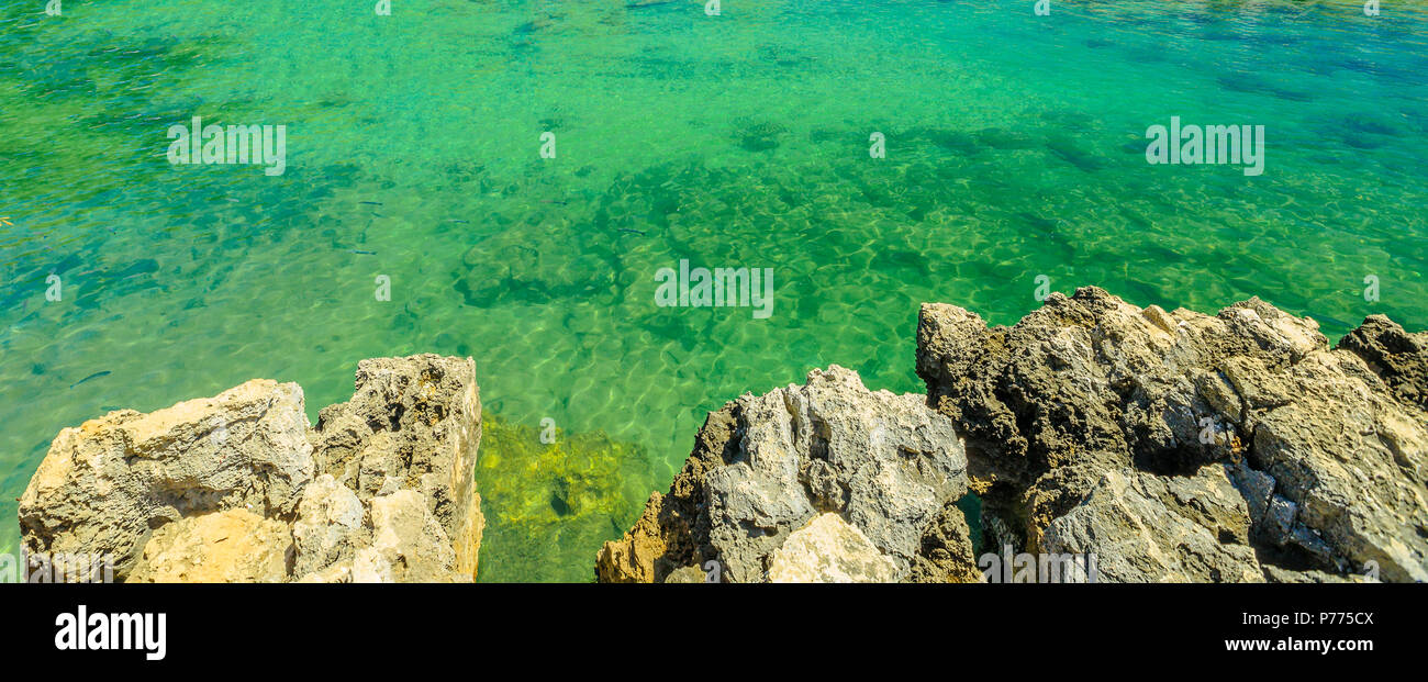 Background texture of coastline reef with cliffs in Portugal with clear green clear water. Copy space. Horizontal panorama. Stock Photo