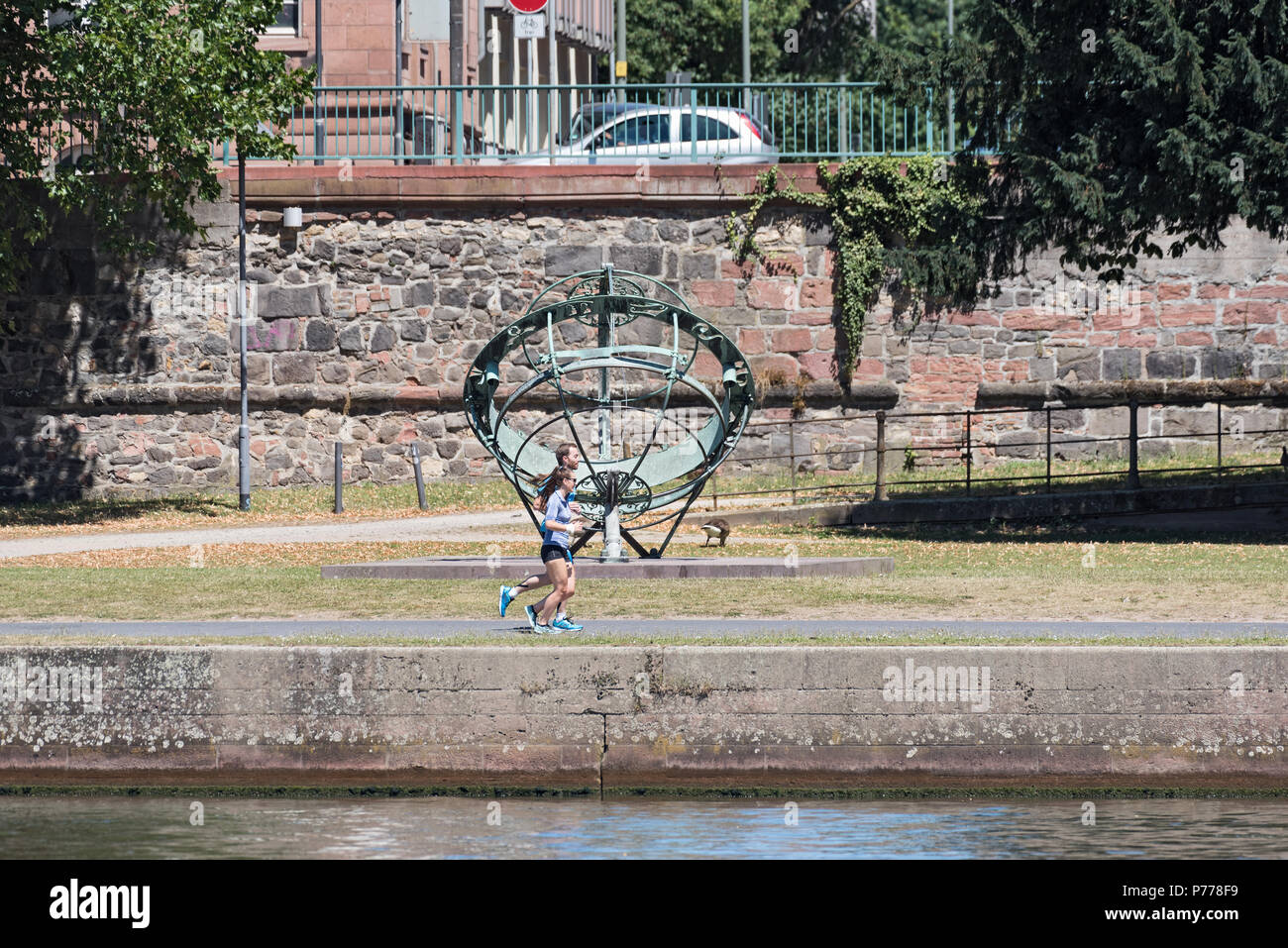 two joggers in front of the equatorial sundial on the river bank, frankfurt am main, germany Stock Photo