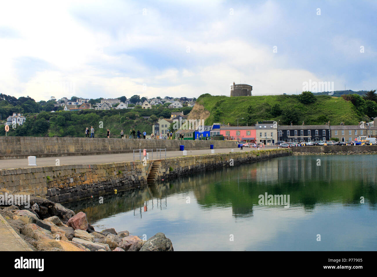 The West Pier of Howth Harbour, Dublin, Ireland with a Martello Tower in the background and a reflective sea. Stock Photo