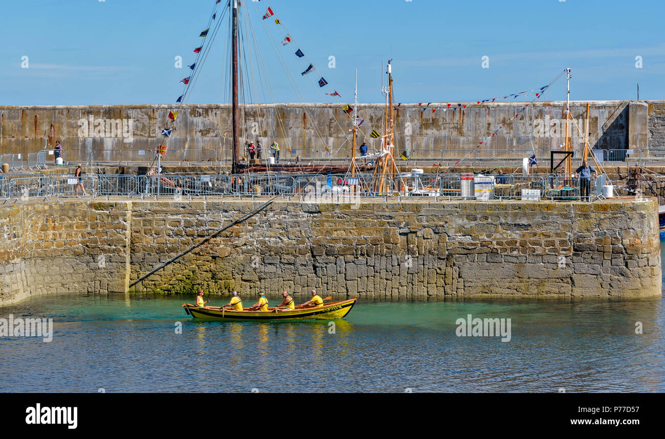 PORTSOY FESTIVAL ABERDEENSHIRE SCOTLAND BOAT RACES YELLOW AVOCH BOAT 164 AND TEAM RETURNING TO HARBOUR Stock Photo