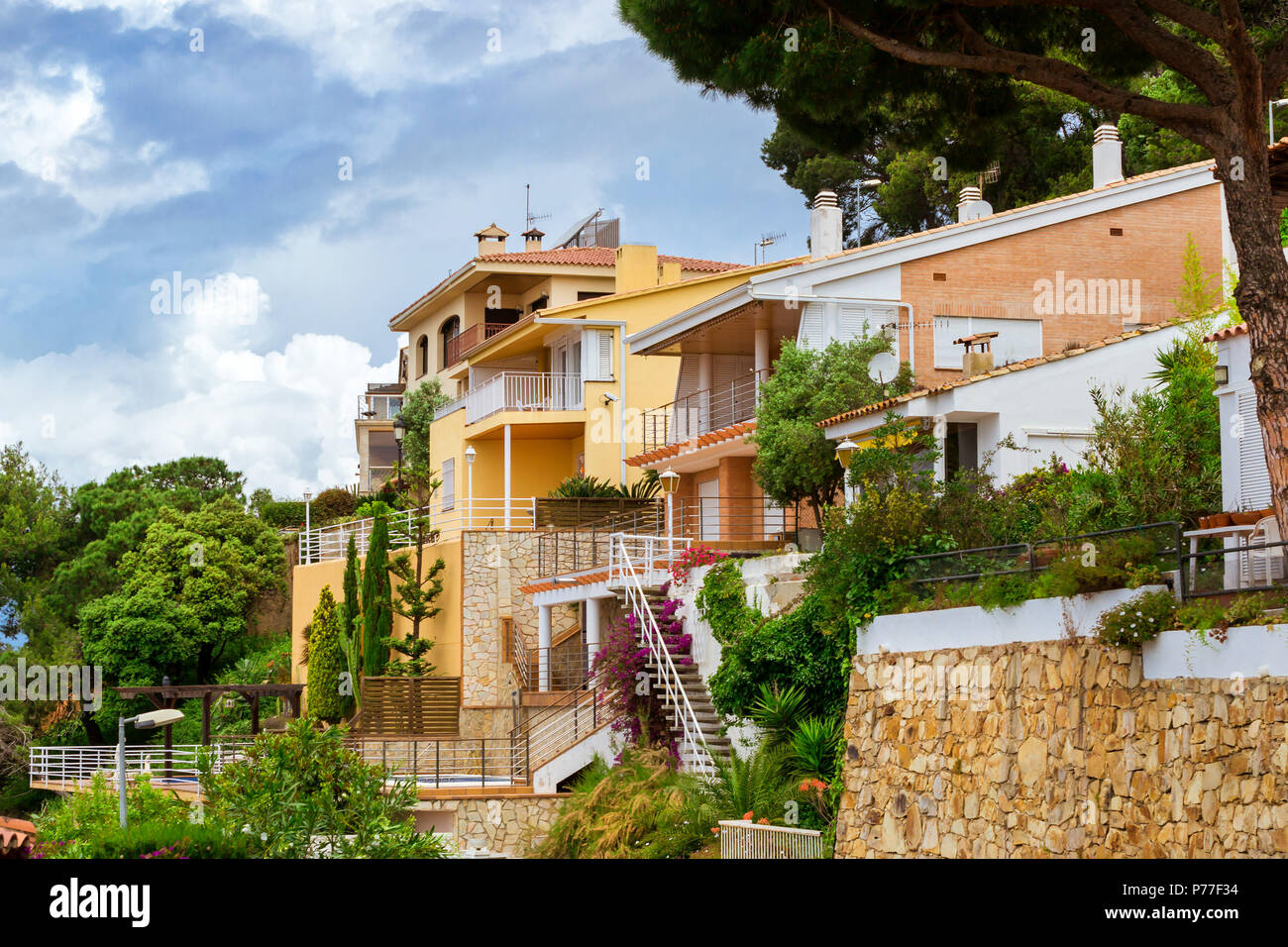 Private stone villas and cottages in a classic Spanish resort style with hedges. Mountain of castle San Juan. Costa Brava, Catalonia, Spain. Architect Stock Photo