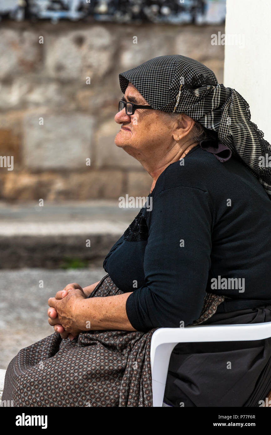 Old lady sits in the central square called Trg Svetog Stjepana outside the cathedral, Hvar, Split-Dalmatia, Croatia. Stock Photo