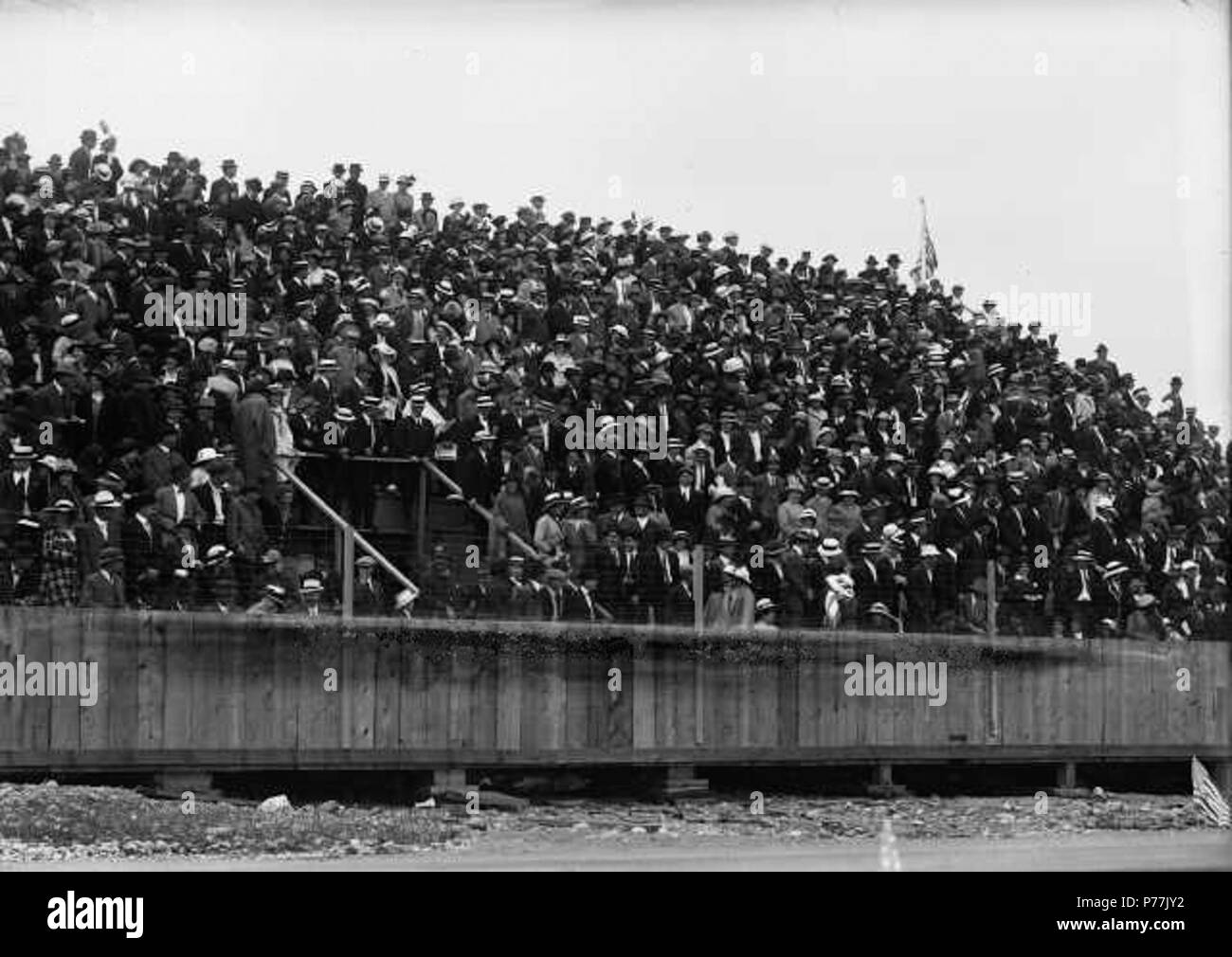 English: Crowds in stands at Tacoma Speedway July 4th - probably 1914. In 1914, over 35,000 spectators packed the grandstand and lined the field fences at the closing race of the Montamara Festo season. They had paid $1.00 for field admission and from $1.50 to $3.00 for the grandstand. The auto racing was possibly the highlight of the abbreviated July 2-4th week which featured fireworks, shows, spectacles and vaudeville. It cost the city about $100,000 to put on the annual event. There were three sanctioned races at the Tacoma Speedway with a total prize of $10,500 which drew entries from the  Stock Photo