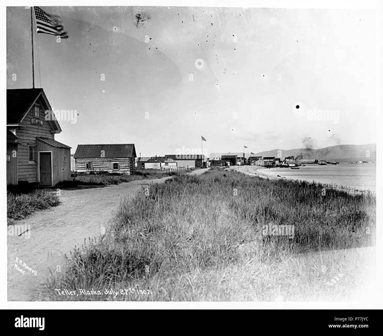 . English: Teller, July 27, 1907 . English: Caption on image: Teller, Alaska, July 27th 1907. F.H. Nowell, Nome, 5534 Teller is located on a spit between Port Clarence and Grantley Harbor, 55 miles southeast of Cape Prince of Wales, Seward Peninsula. Originally called Nooke by the Eskimo people of the area, who used it for the purpose of catching and drying fish, this location was used in the winter of 1866-67 as quarters by Capt. Daniel Libby's section of the Western Union Telegraph Expedition and was known as Libbysville or Libby Station. It is doubtful that any permanent settlement was esta Stock Photo