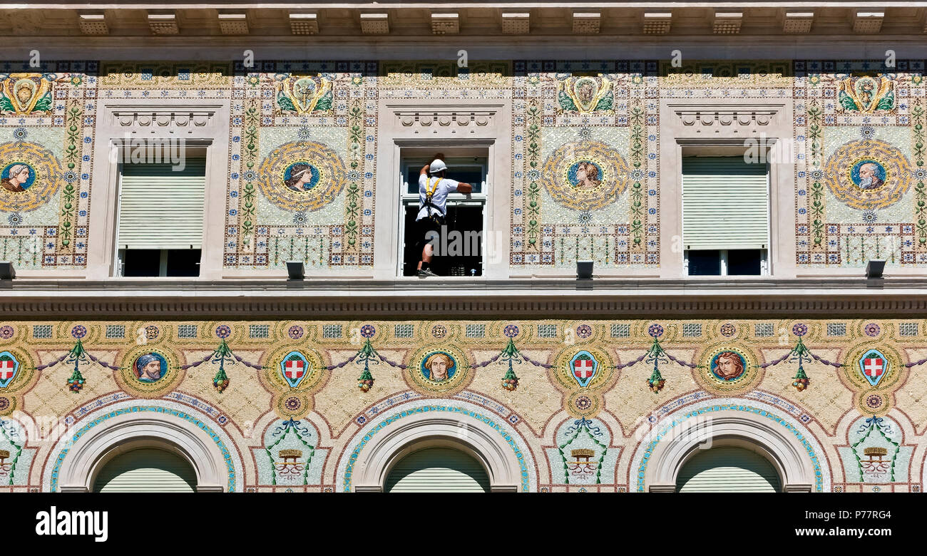 Workman wearing a harness, cleaning windows glasses. Dangerous work. Government Building, Unity Square. Palazzo del Governo.Trieste, Italy, Europe. Stock Photo