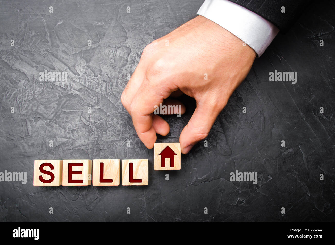 The hand of the realtor puts a cube with a picture of the house to the word sale. Concept of selling a house, apartment, real estate. The market of im Stock Photo