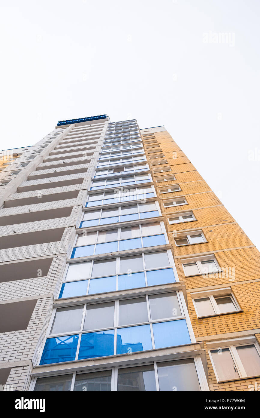 Bottom up view to corner of facade multi-storey yellow modern residential building. Stock Photo