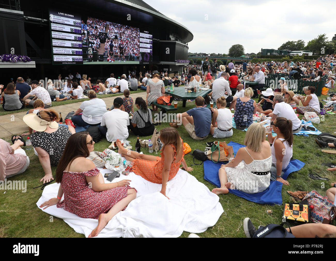 Spectators watch the big screen on Murray Mound on day three of the Wimbledon Championships at the All England Lawn Tennis and Croquet Club, Wimbledon Stock Photo