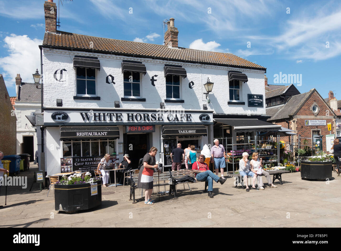 People relaxing with ice creams outside the White Horse Café in Thirsk Market Place in the town centre on a warm summer day Stock Photo