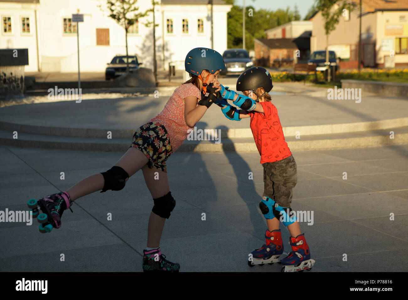 two children playing/dancing on roller skates on city square Stock