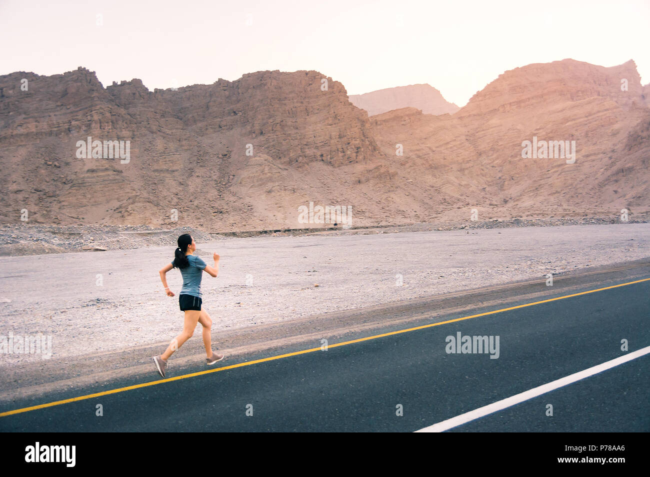 Girl running on the desert road, outdoor workout Stock Photo