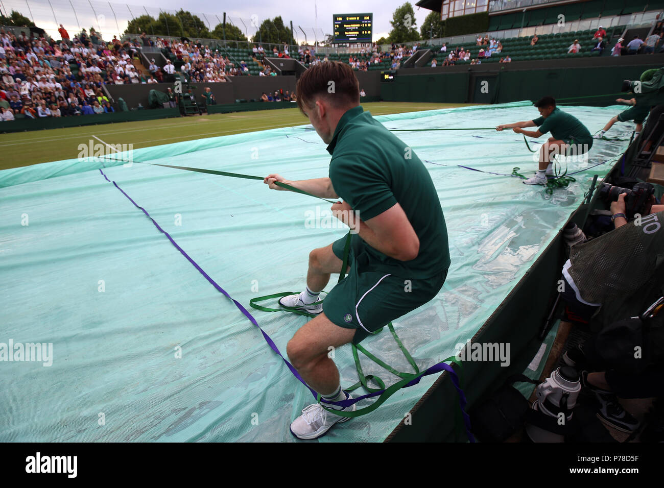 Covers are pulled back on court three following a rain delay on day three of the Wimbledon Championships at the All England Lawn tennis and Croquet Club, Wimbledon Stock Photo