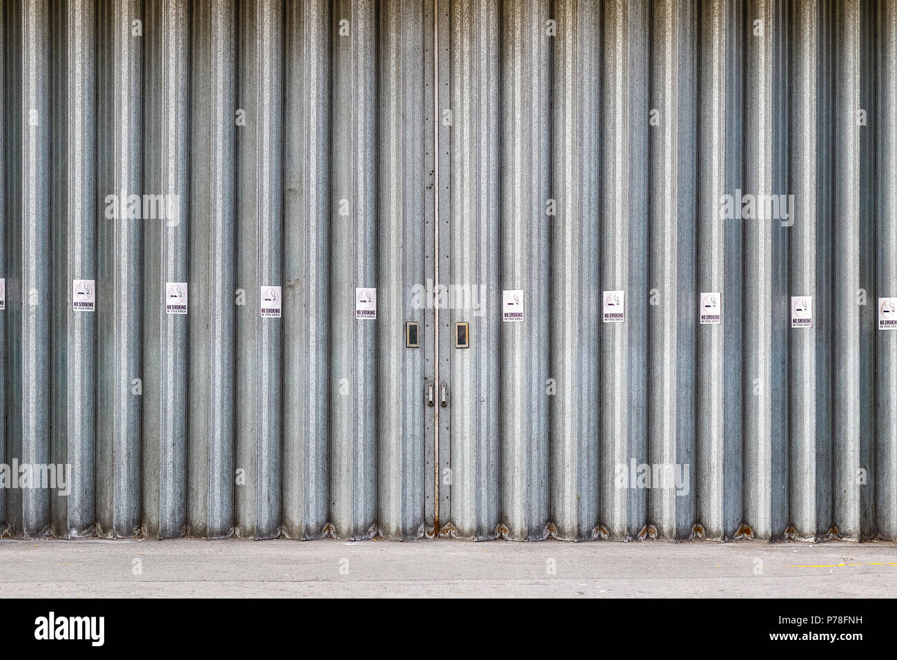 Sliding and folding industrial doors with No Smoking signs, a loading bay for delivery truck on a street of London city Stock Photo