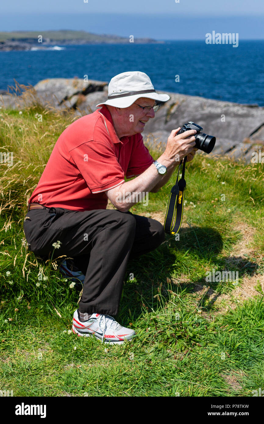 Older man taking landscape photographs wearing floppy sunhat Stock Photo