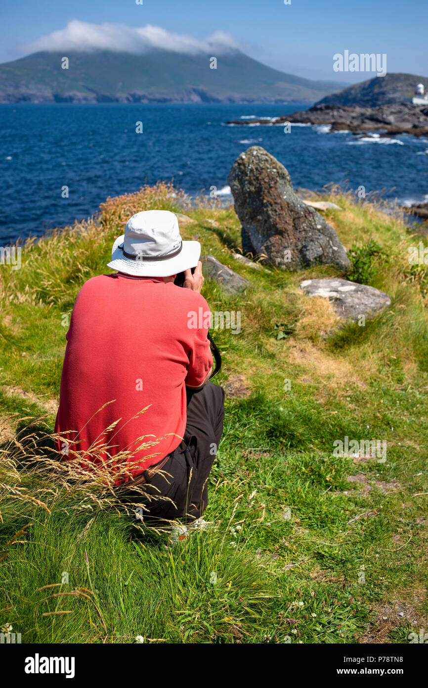 Older man taking landscape photographs wearing floppy sunhat Stock Photo