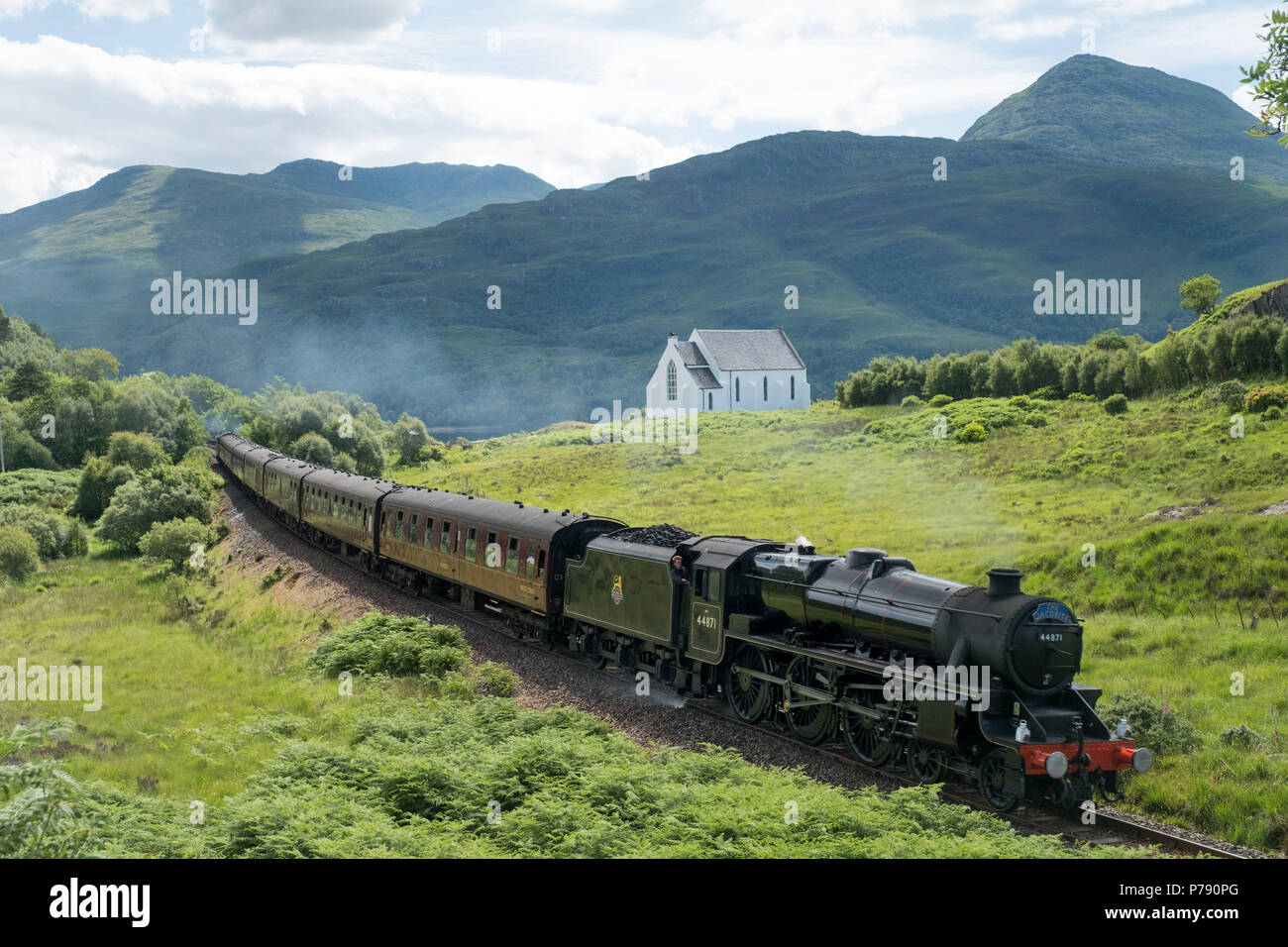 The Jacobite Express, ( Hogwarts Express) passes Our Lady of the Braes Roman Catholic Church near Polnish on the Forth William to Mallaig line. Stock Photo