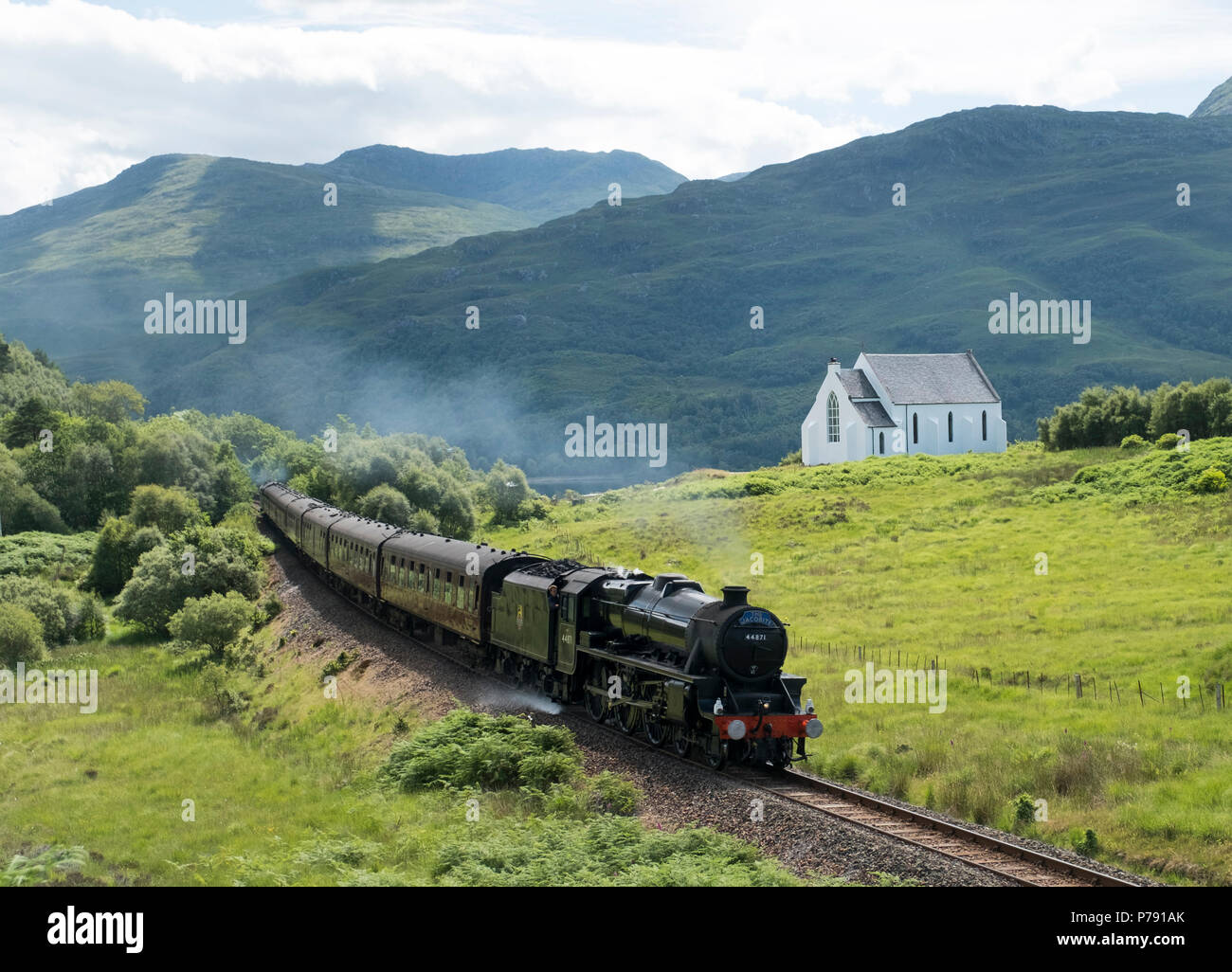 The Jacobite Express, ( Hogwarts Express) passes Our Lady of the Braes Roman Catholic Church near Polnish on the Forth William to Mallaig line. Stock Photo