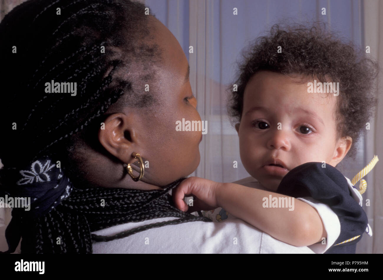 Black mother holding her unhappy mixed race baby girl Stock Photo