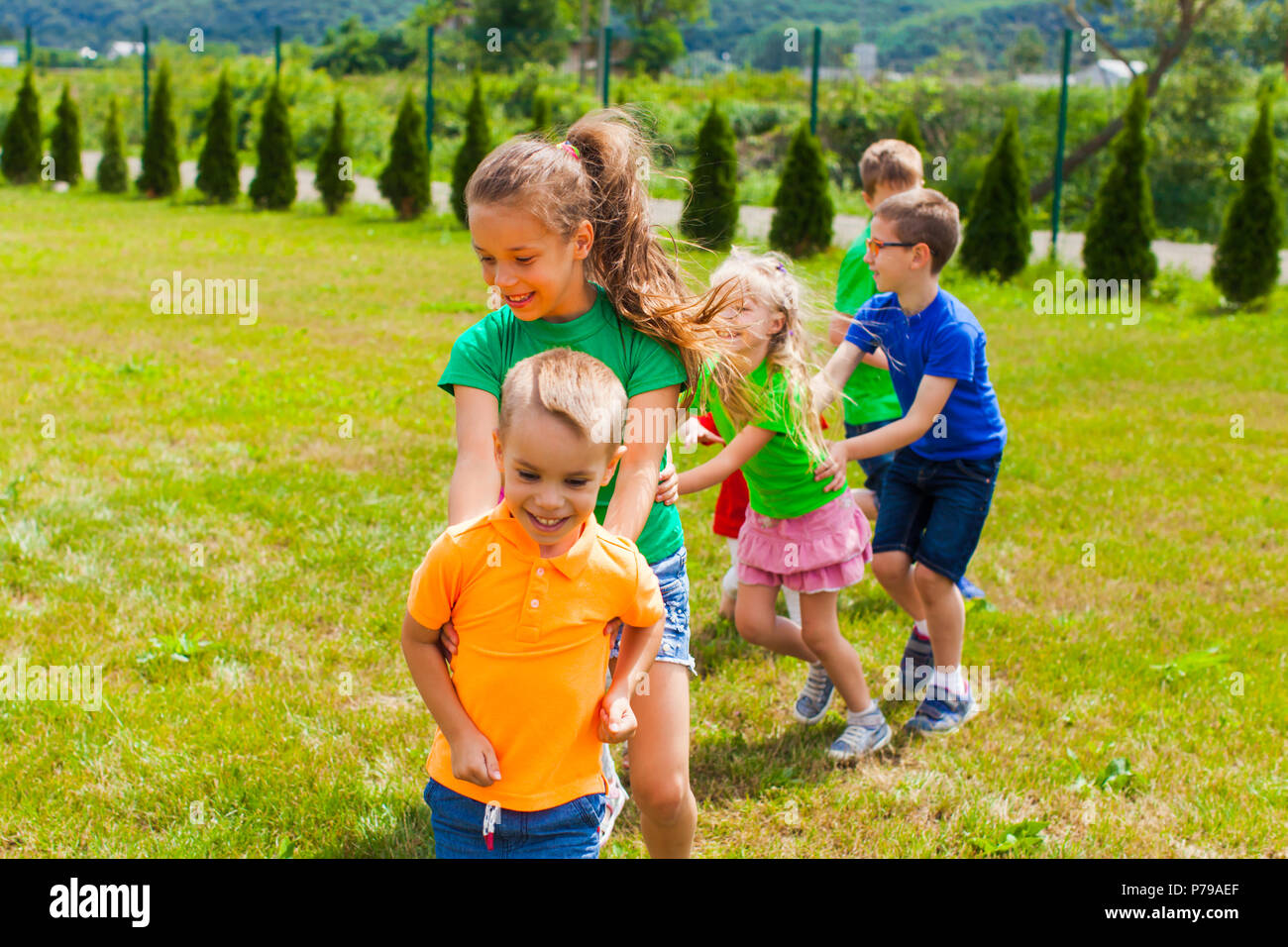 Laughing children playing tail of a dragon Stock Photo