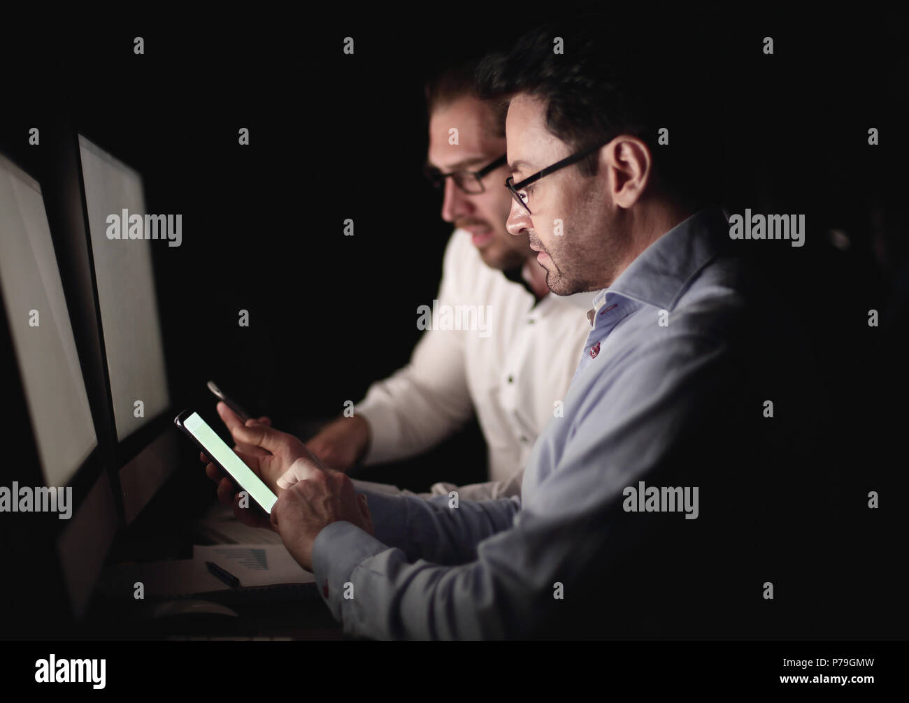 colleagues using smartphones while sitting at a Desk Stock Photo