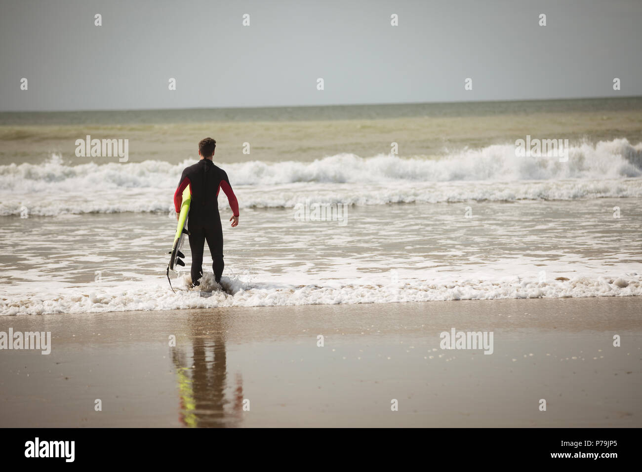 Surfer with surfboard looking at the sea from beach Stock Photo