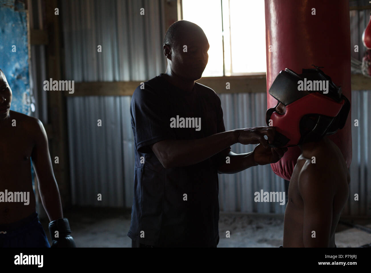 Trainer assisting male boxer to wear headgear Stock Photo Alamy