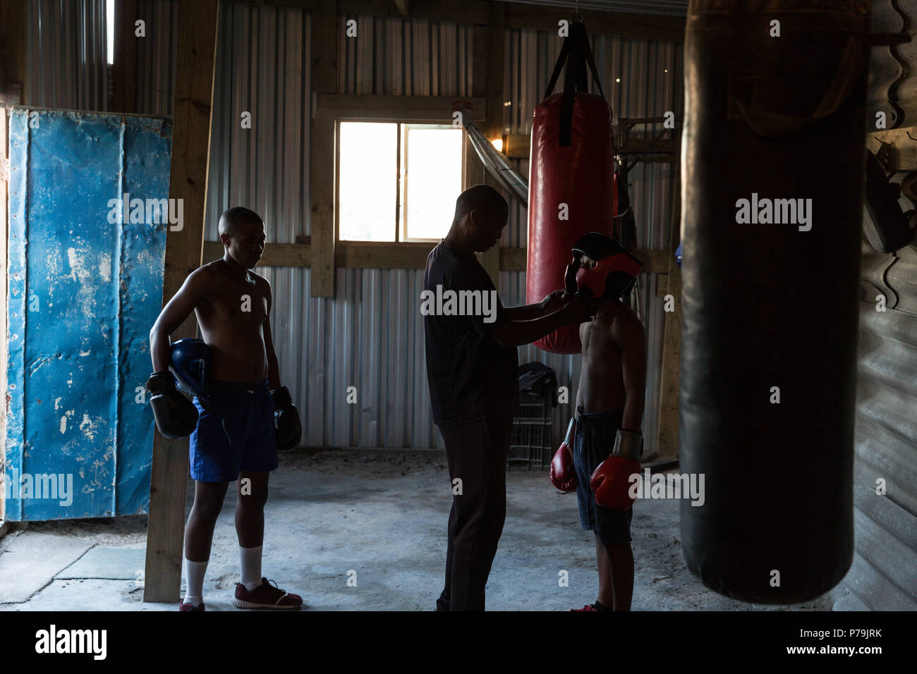 Trainer assisting male boxer to wear headgear Stock Photo