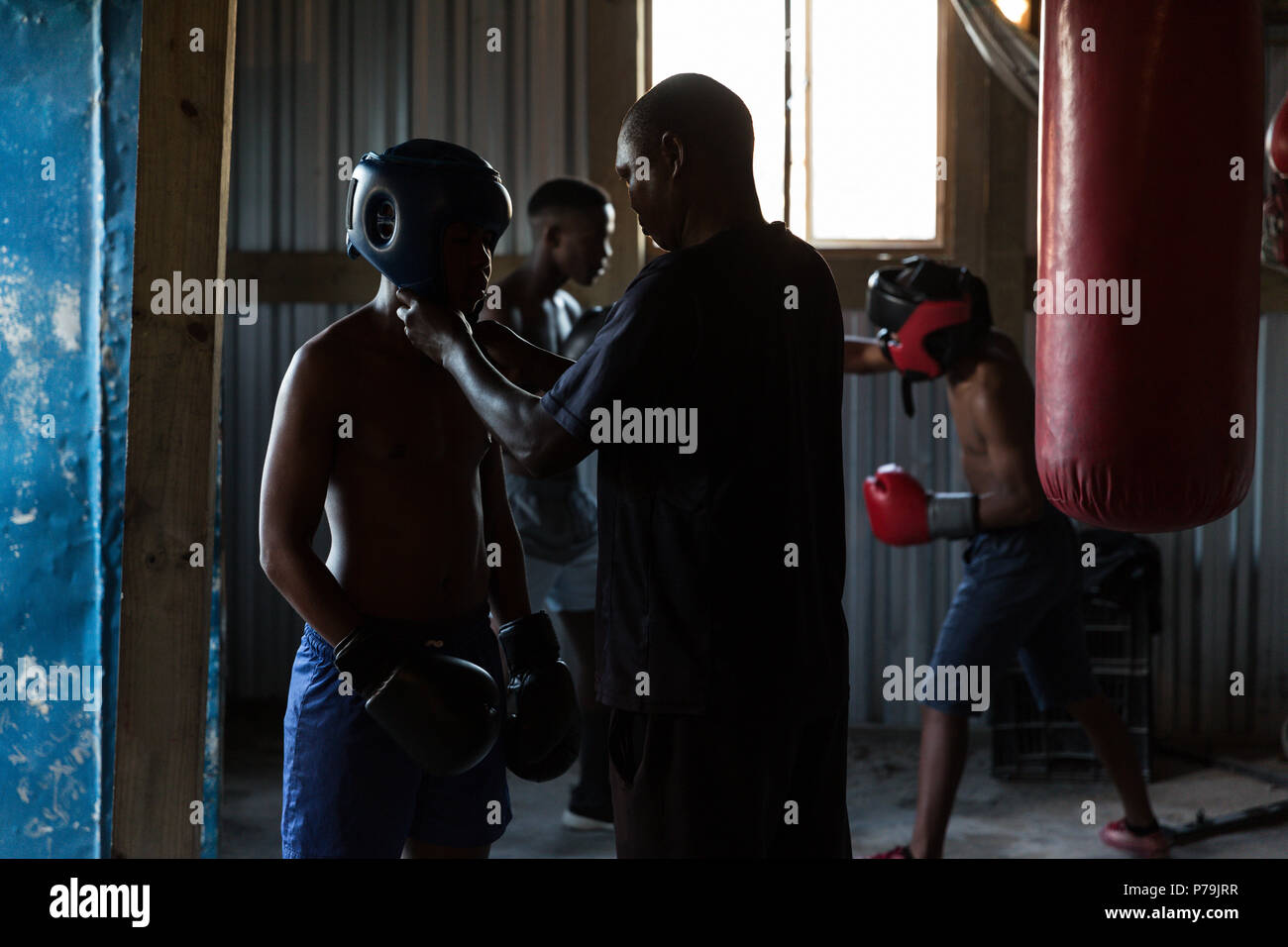 Trainer assisting male boxer to wear headgear Stock Photo Alamy