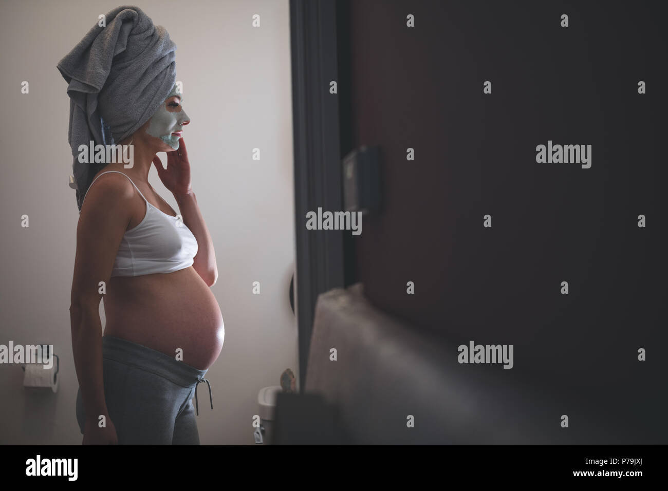 Pregnant woman with facial cream in bathroom Stock Photo