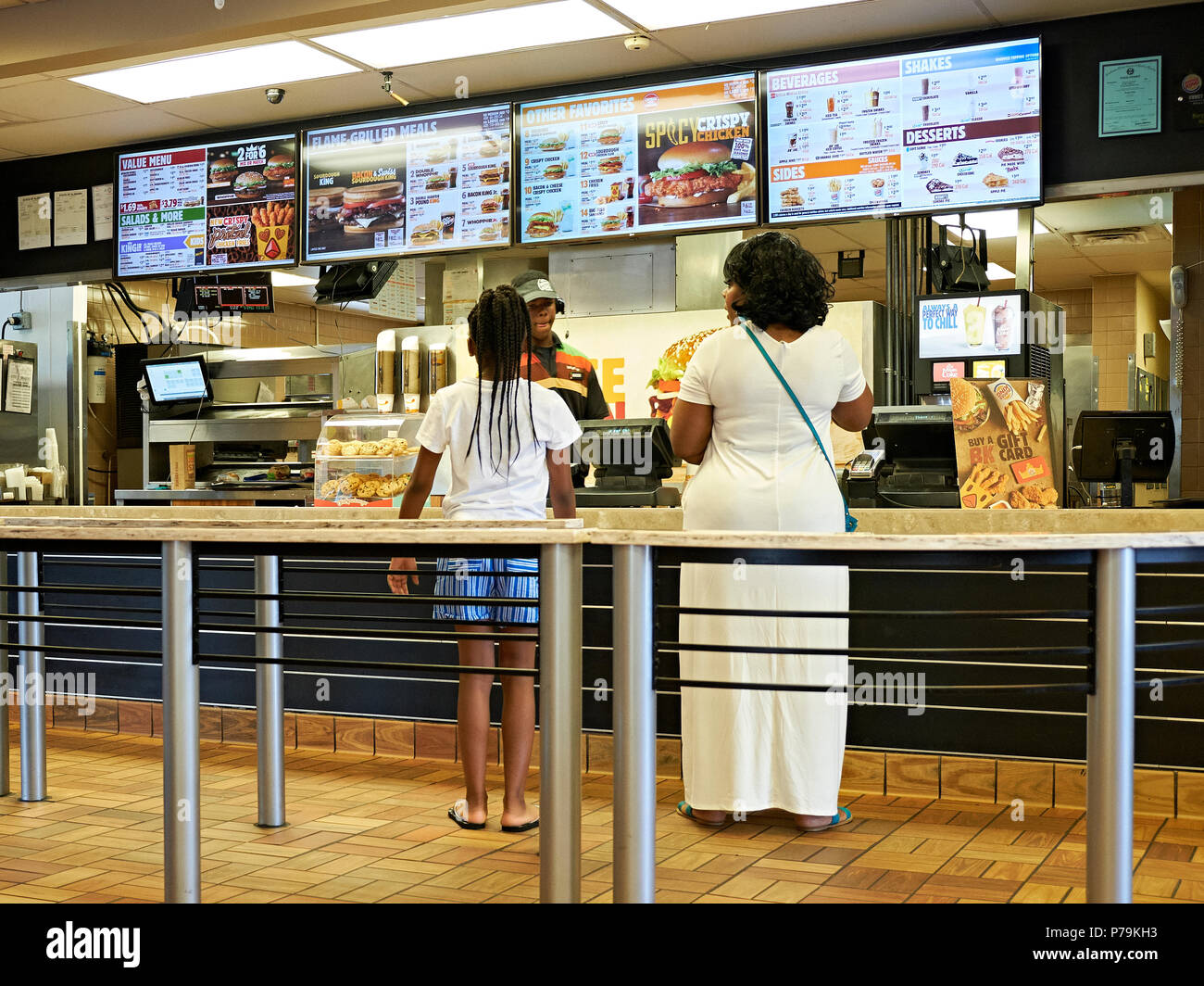 Woman and young girl being served inside in line at a Burger King fast food restaurant in Montgomery Alabama, USA. Stock Photo