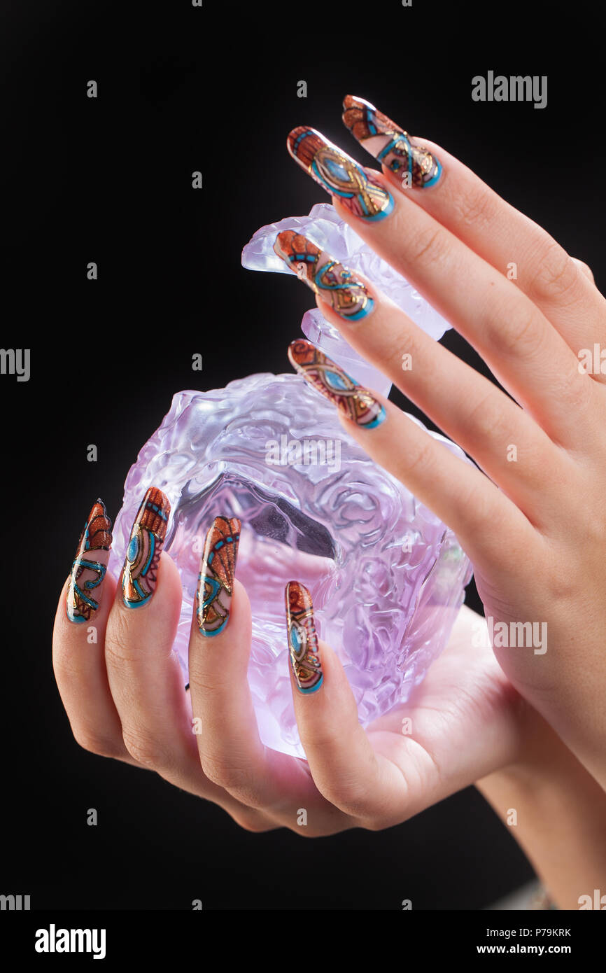 Woman's hand with nail art and glass on a black studio background Stock Photo