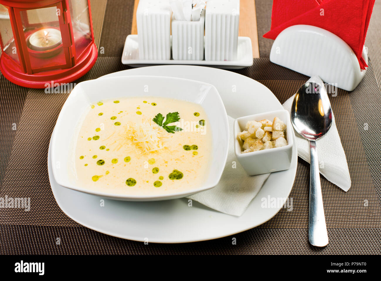 ceramic white plate with cheese cream soup on table in restaurant Stock Photo