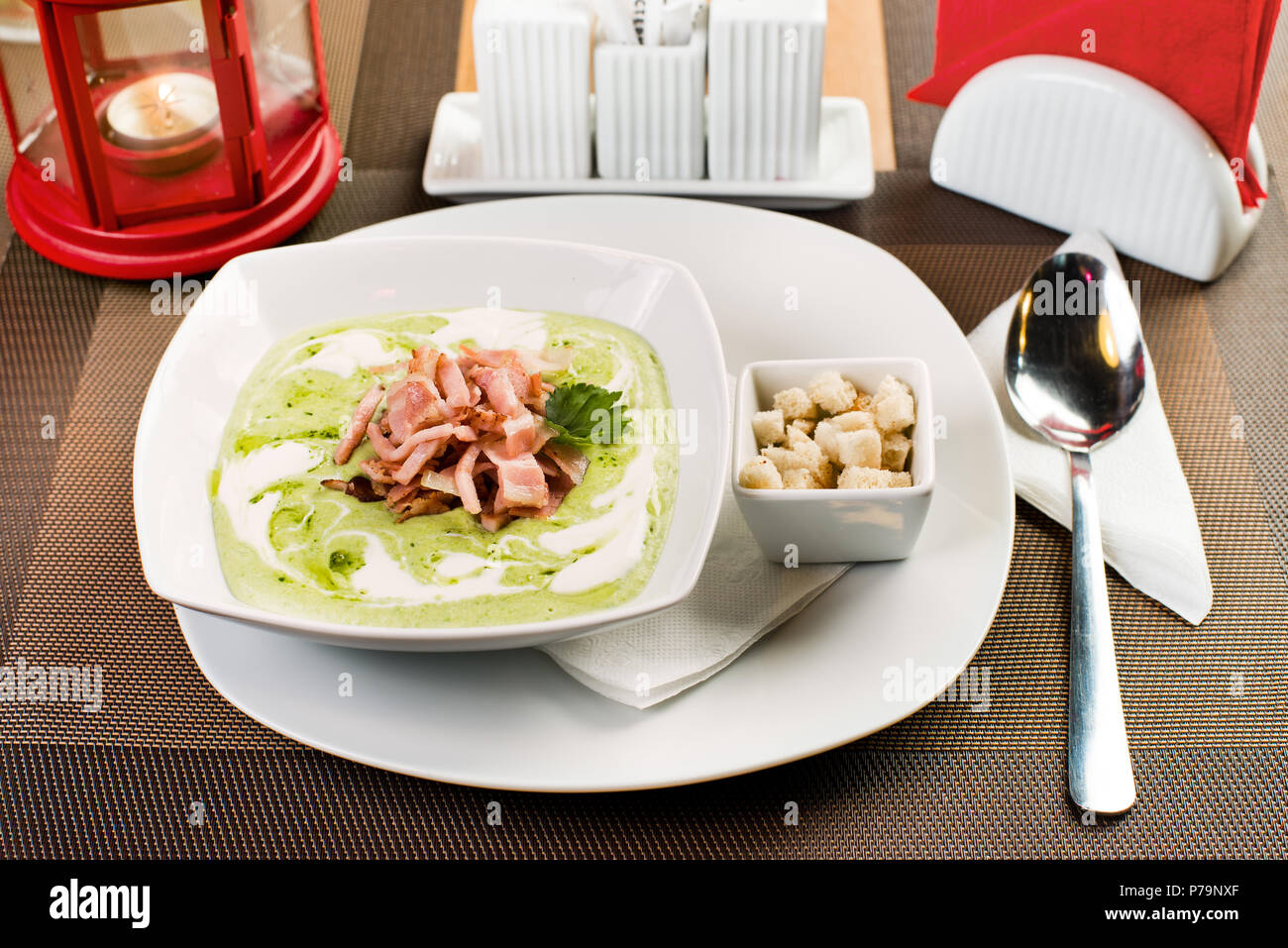 ceramic white plate with  cream soup with ham, on table in restaurant Stock Photo