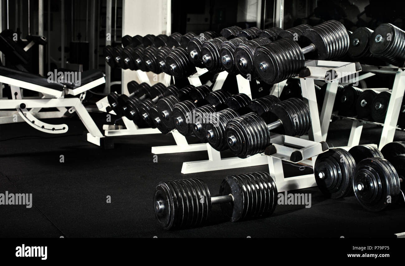 many black dumbbells in dark weight room, horizontal photo Stock Photo