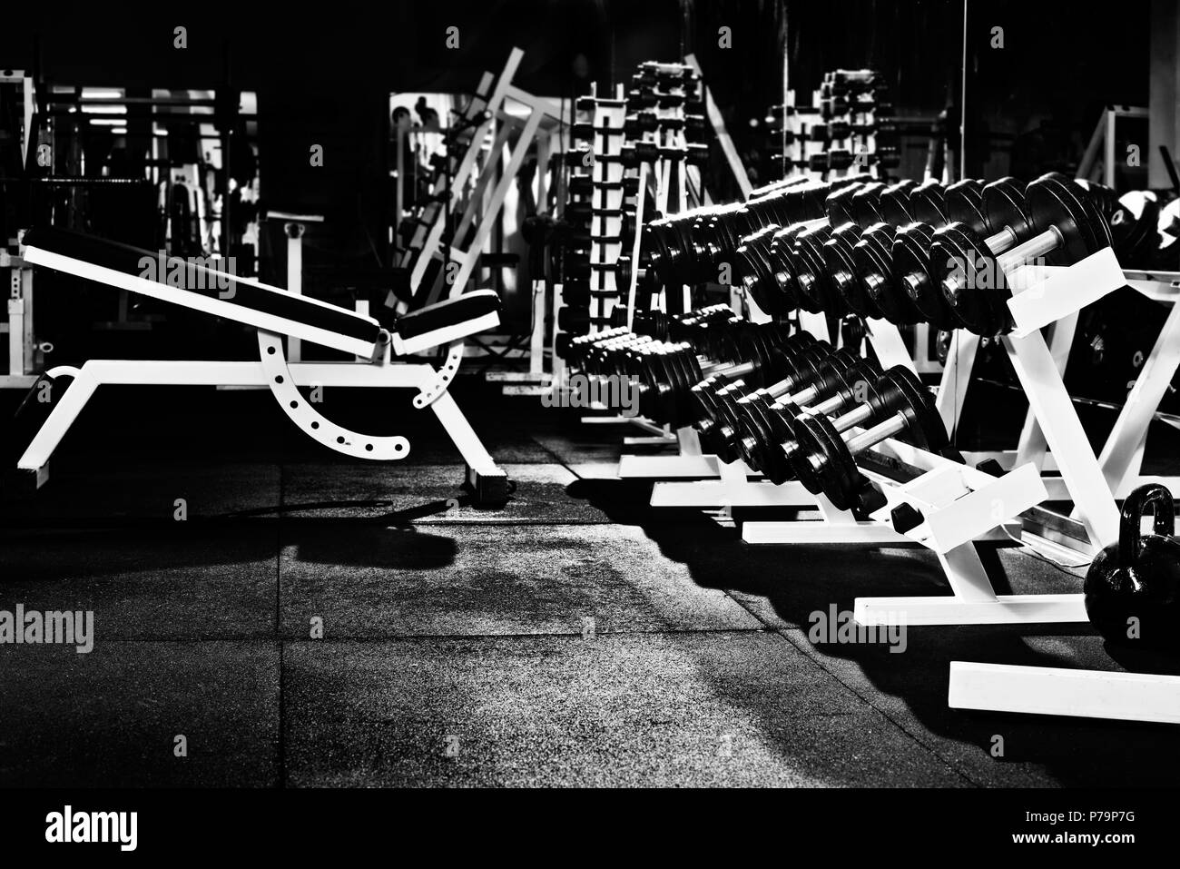 many black dumbbells in dark weight room, horizontal photo Stock Photo