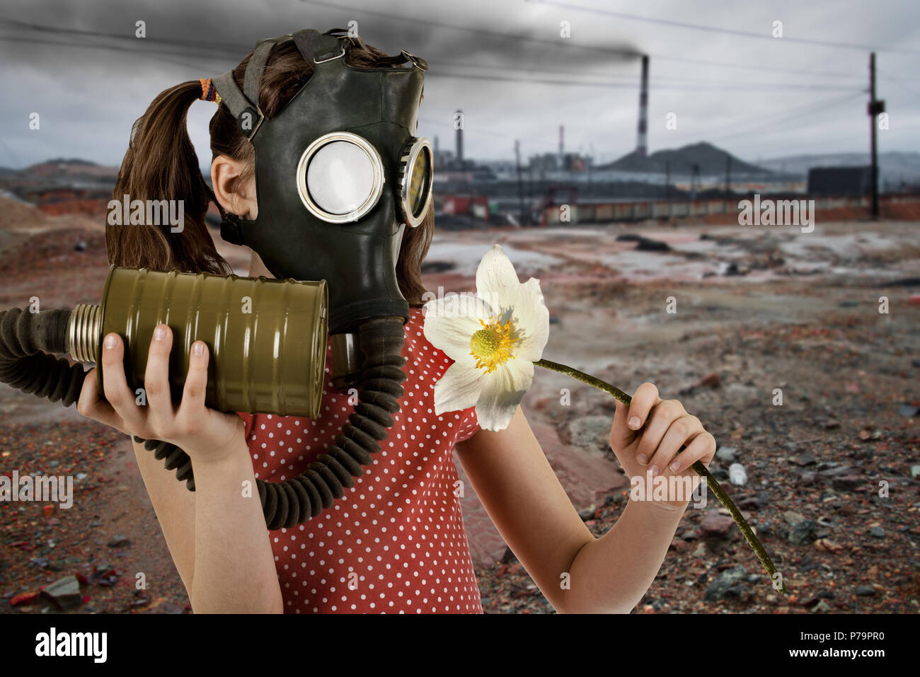 little girl  in gas mask, smell big white flower Stock Photo