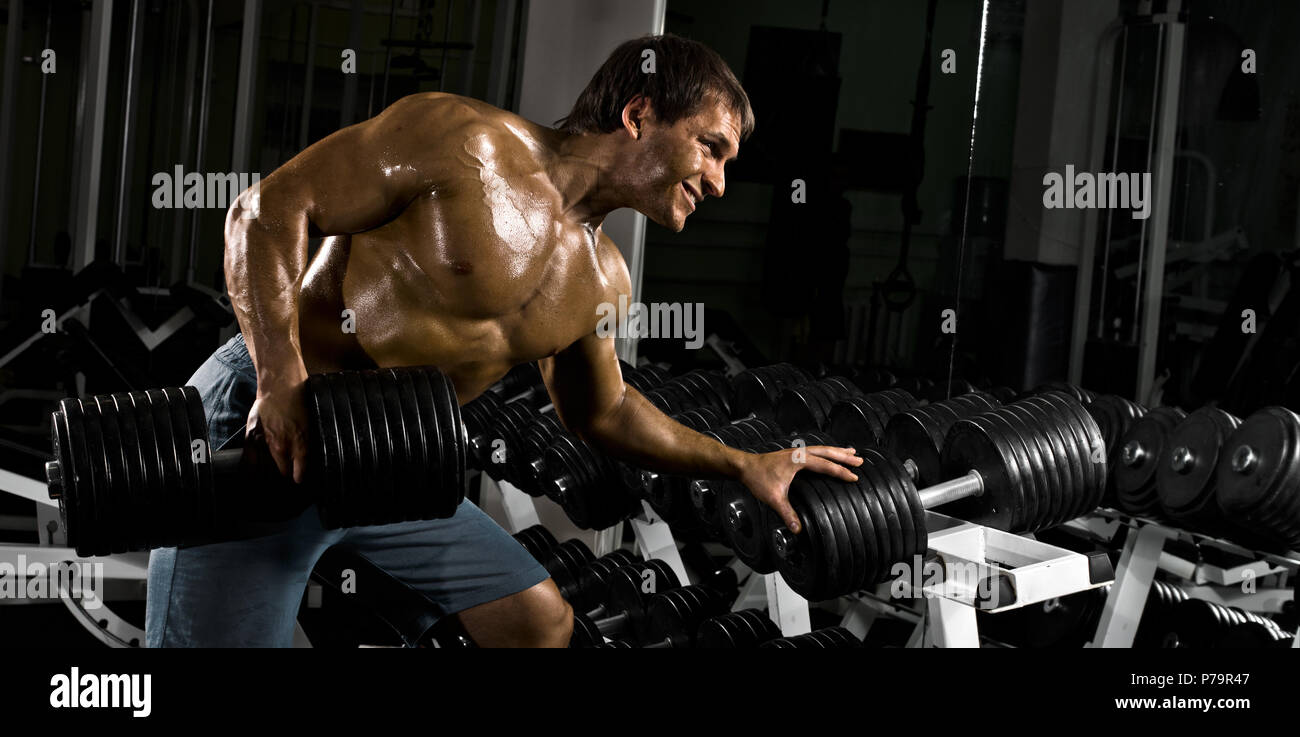 hard workout. Muscular black man doing exercises with dumbbells for back at  gym Stock Photo - Alamy